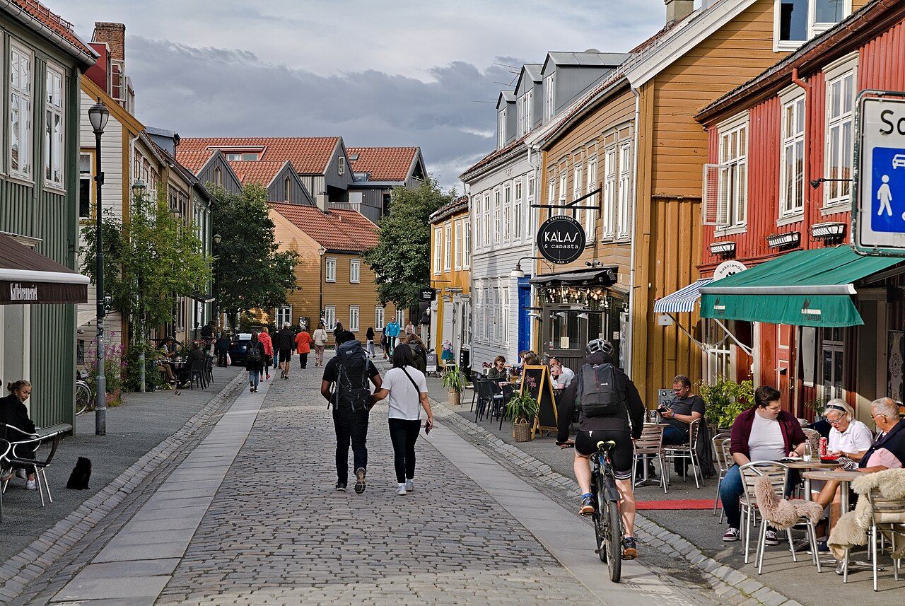 Colourful wooden houses, cafés and cyclists on a cobbled street in Bakklandet, Trondheim