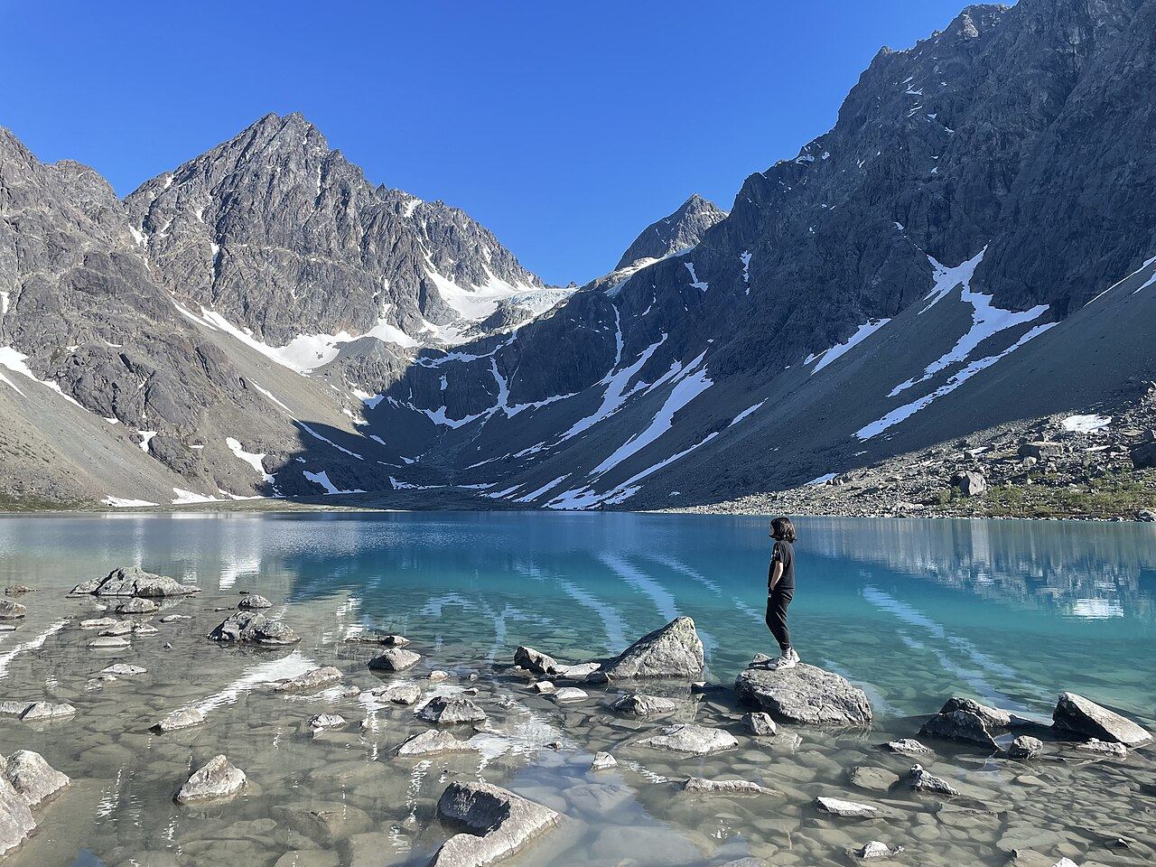 Turquoise glacier water of Blåisvatnet below jagged grey peaks in the Lyngen Alps