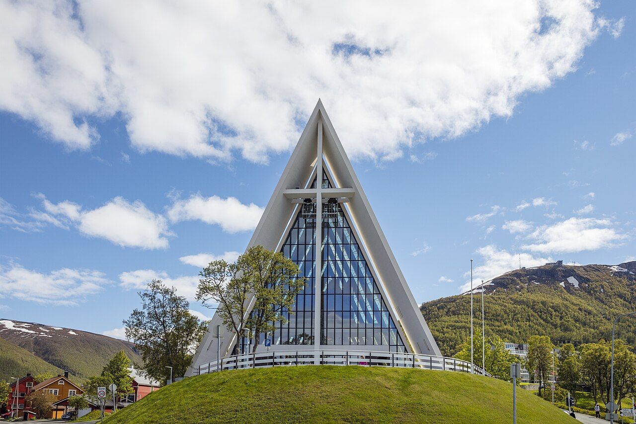 The white, triangular Arctic Cathedral in Tromsø under a blue sky with drifting clouds
